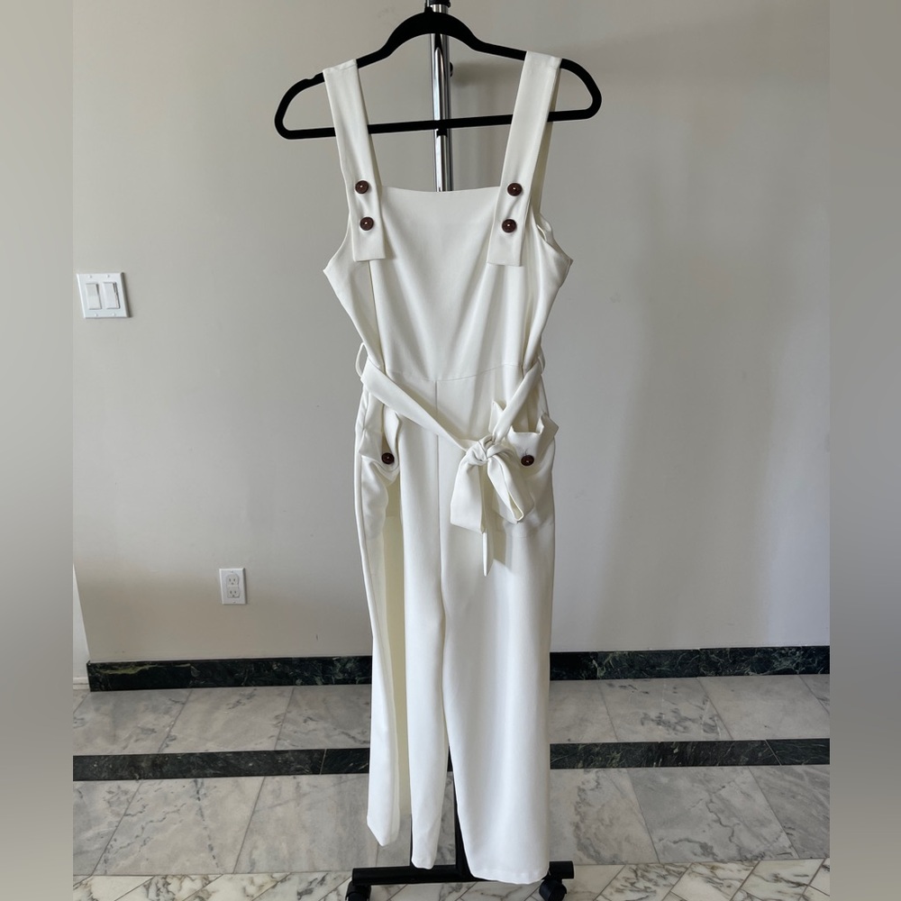 White jumpsuit with brown buttons and pockets.